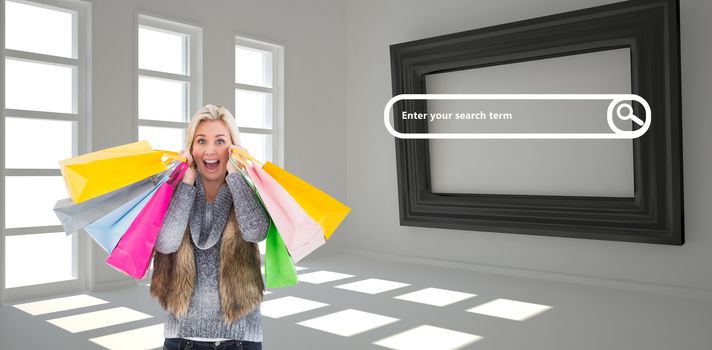 Blonde in winter clothes holding shopping bags against dark white room with frame at wall