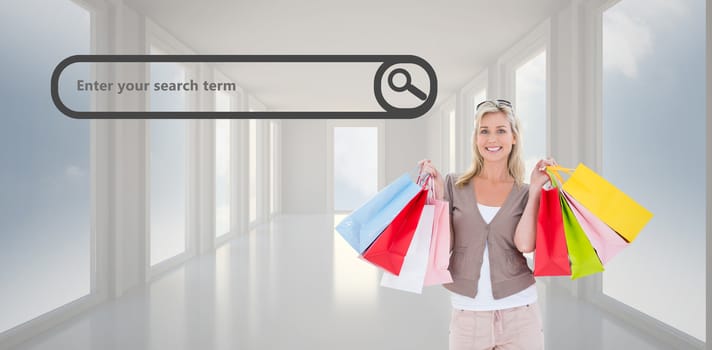 Happy blonde holding shopping bags against bright white hall with windows