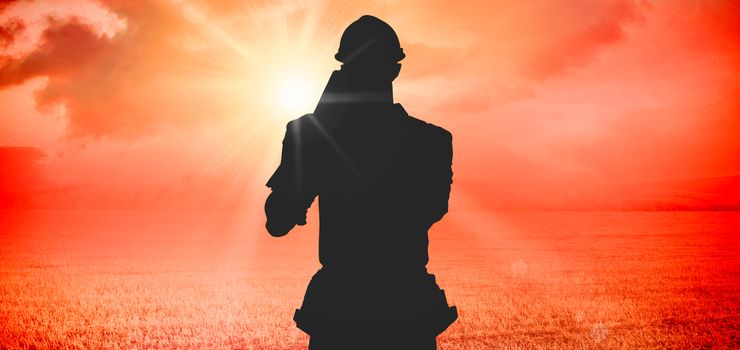 Happy carpenter carrying wooden planks against sunrise over field