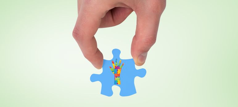Hand holding jigsaw piece against green vignette