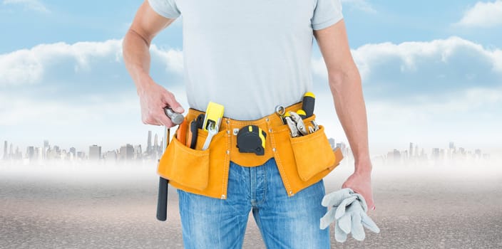 Technician holding gloves and hammer against city on the horizon