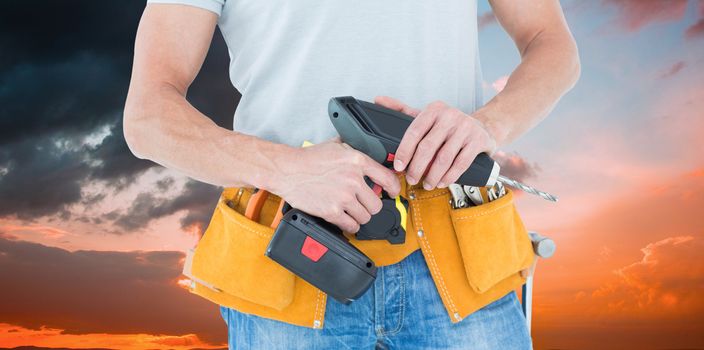 Repairman holding handheld drill against orange and blue sky with clouds