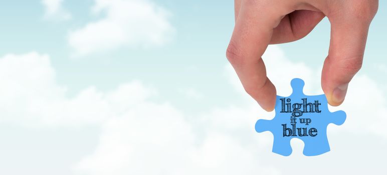 Hand holding jigsaw piece against blue sky