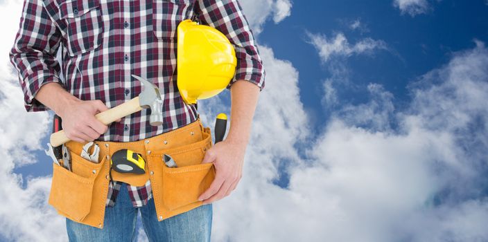 Repairman with hard hat and hammer against bright blue sky with clouds