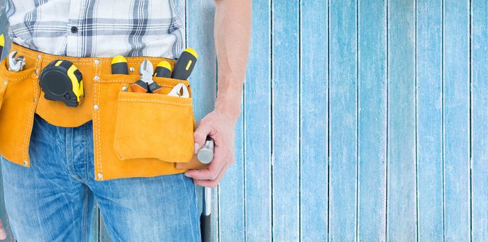Technician with tool belt around waist against wooden planks