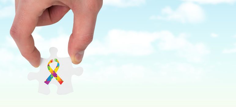 Hand holding jigsaw piece against blue sky