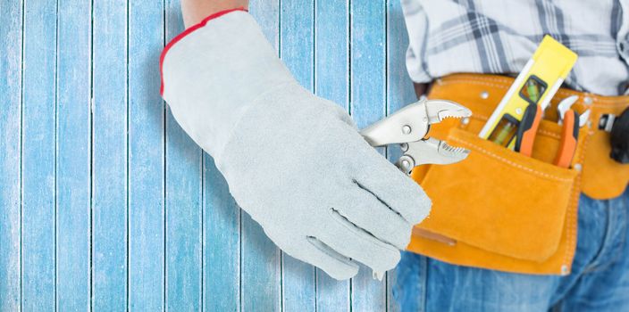 Technician using pliers over white background against wooden planks
