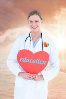 The word education and doctor holding red heart card  against sunrise over magical sea