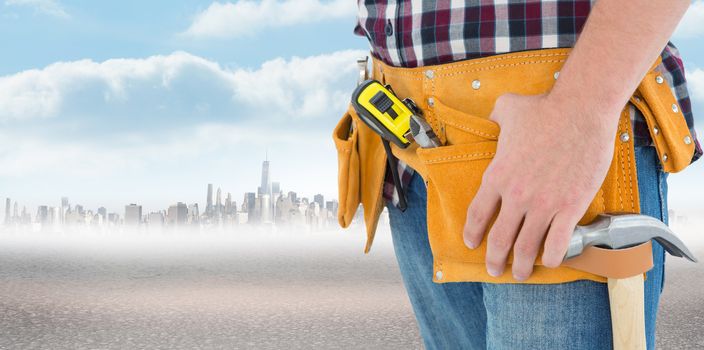 Close-up of male repairman wearing tool belt against city on the horizon