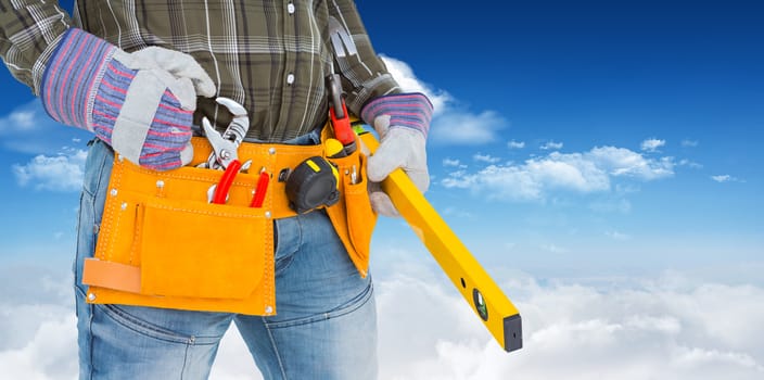 Handyman holding spirit level against bright blue sky with clouds