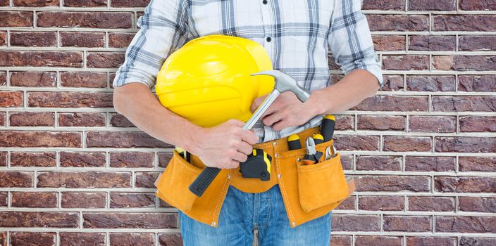 Technician holding hammer and hard hat against red brick wall
