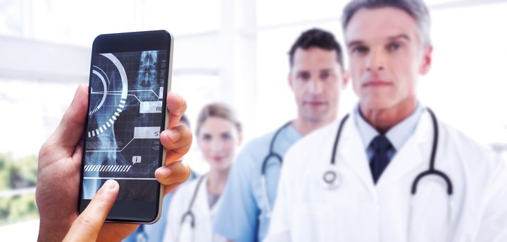 hand holding smartphone against serious medical team in row