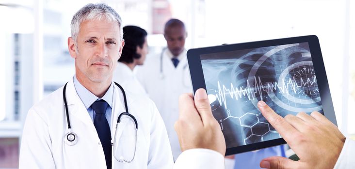 Man using tablet pc against mature doctor pointing at something on his clipboard