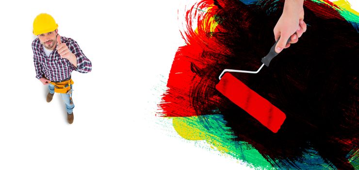 Handyman holding paint roller  against red green black yellow and blue paint
