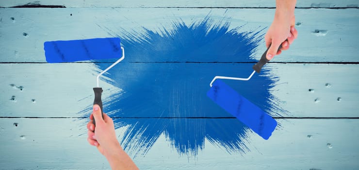 Handyman holding paint roller  against painted blue wooden planks