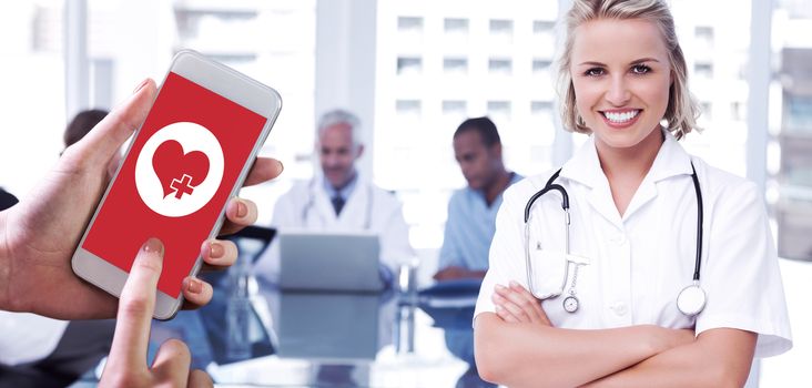 Hand holding smartphone against nurse with arms crossed