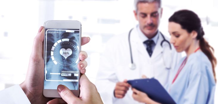 Hand holding smartphone against nurse and doctor looking a file 