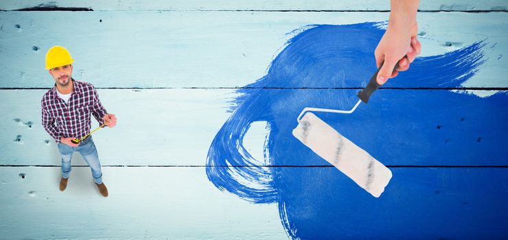 Handyman holding paint roller  against painted blue wooden planks