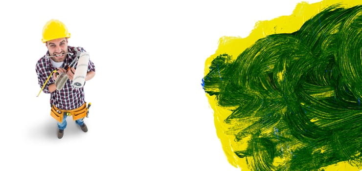 Frustrated handyman holding various tools against blue and yellow paint making green