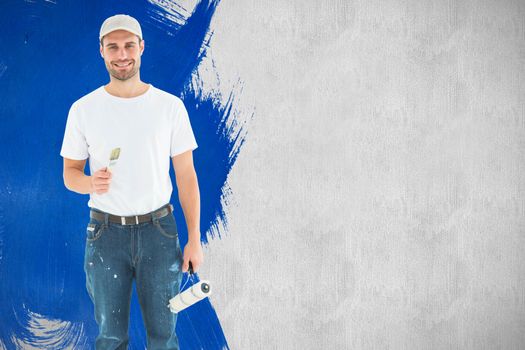 Happy man holding paint roller and paintbrush against white and grey background
