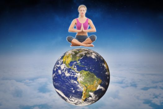 Calm blonde sitting in lotus pose with hands together against white clouds under blue sky