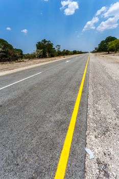 Endless road in Namibia, Caprivi Game Park, with blue sky