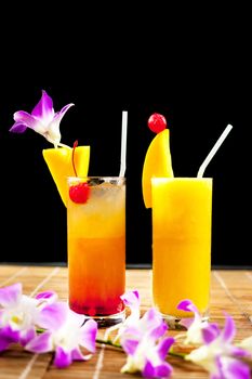 Mango juice and juice soda with fruit on glass near beautiful flower isolation black background .