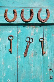 old rusty historical key and luck symbol horseshoe on wooden green farm wall