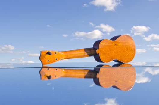 small kids wooden  guitar toy on mirror and sky