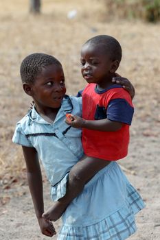 NAMIBIA, KAVANGO, OCTOBER 15: Unidentified Namibian girl carries her small brother in her arms. Kavango region near Rundu. October 15, 2014, Namibia