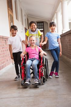 Cute disabled pupil smiling at camera with her friends at the elementary school