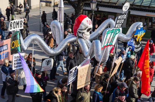 Munich, Germany - February 7, 2015: Antiwar march procession against expansion of presence North Atlantic Alliance in Europe. Protesters and activists are bearing dummy of octopus with NATO skull. 