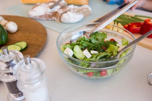 Family preparing salad at home in the kitchen