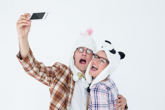 Geeky hipster couple taking selfie with smart phone on white background