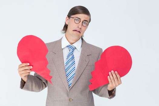 Geeky businessman crying and holding broken heart card on white background 