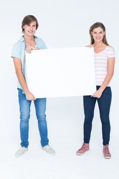 Hipster couple holding poster smiling and at camera on white background