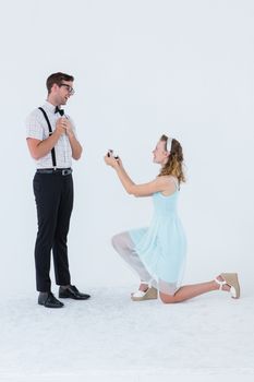 Hipster woman doing a marriage proposal to her boyfriend on white background
