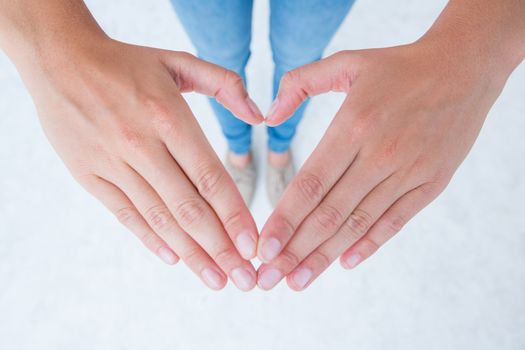 Woman making heart shape with hands on white background