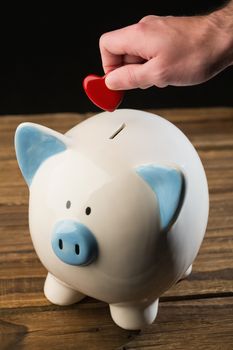 Hand putting heart in piggy bank shot in studio