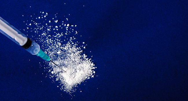 Medical syringe and drug on blu background