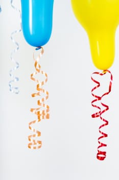 Balloons of different bright colors are hanging on a white background