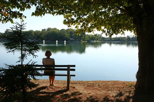Lady relaxing on the bench ashore of lake