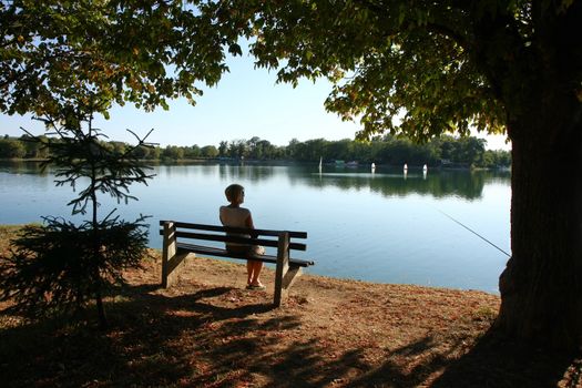 Lady relaxing on the bench ashore of lake