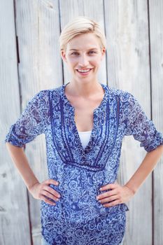 Pretty blonde woman standing hands on hips on wooden background