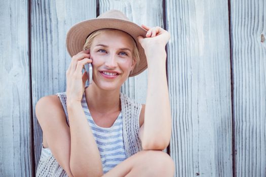 Pretty blonde woman calling on the phone on wooden background