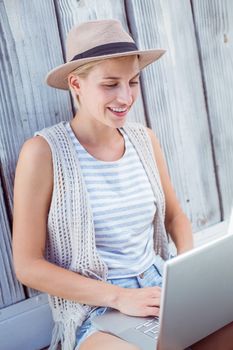 Pretty blonde woman using her laptop on wooden background