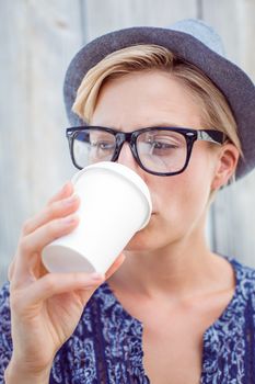 Pretty blonde woman drinking coffee on wooden background