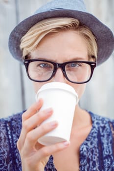 Pretty blonde woman drinking coffee on wooden background