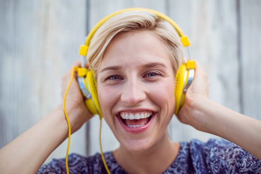 Pretty blonde woman listening music on wooden background