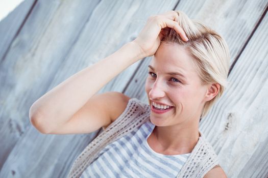 Pretty blonde woman smiling on wooden background